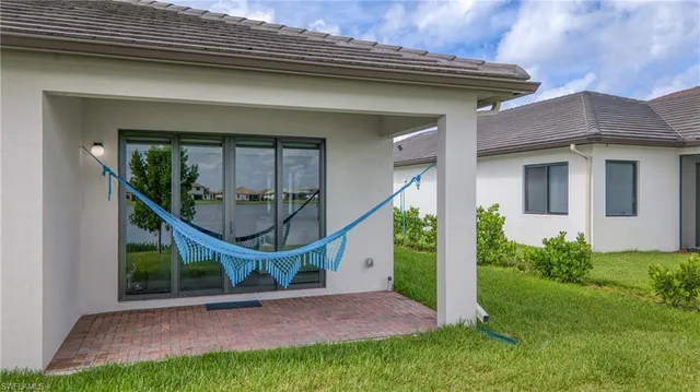 a view of a white house with a big yard and potted plants