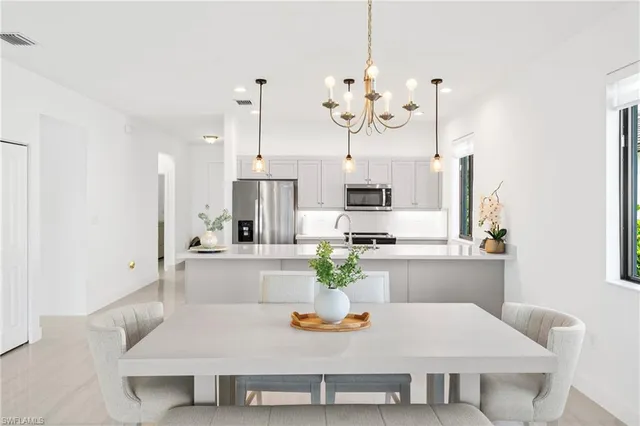 a kitchen with white cabinets and chairs