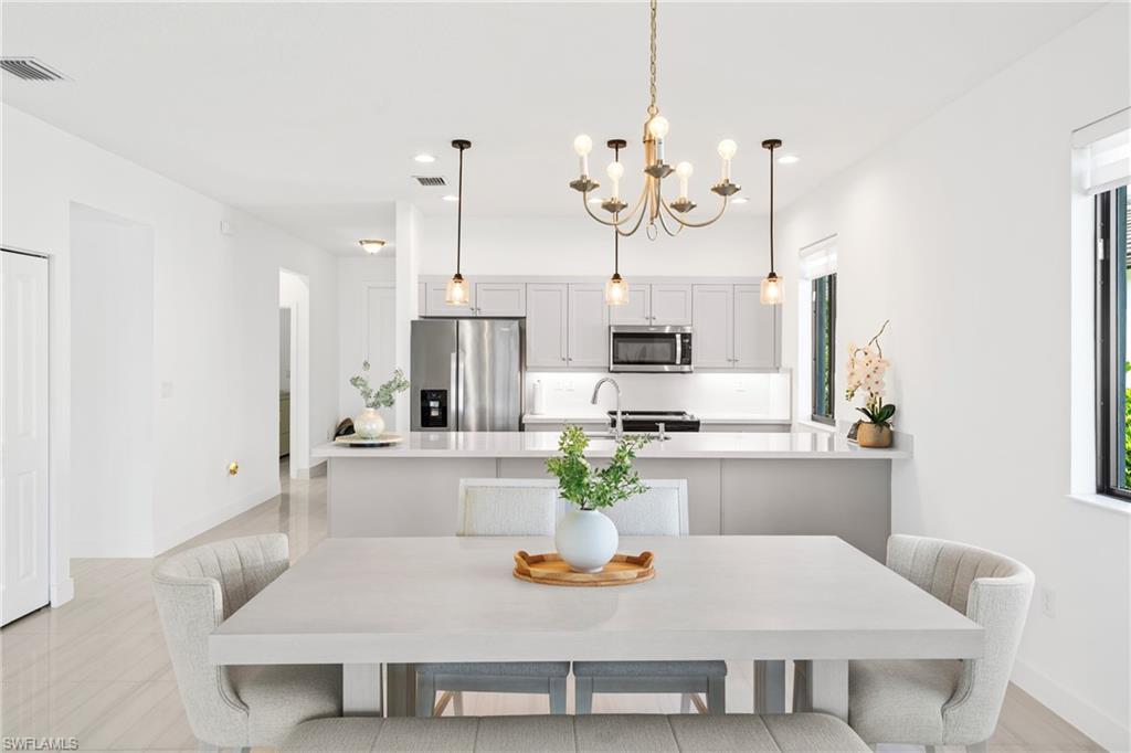 4951 Brigata Way Avenue Immokalee, FL 34142 - Photo 5 of 49 a kitchen with white cabinets and chairs