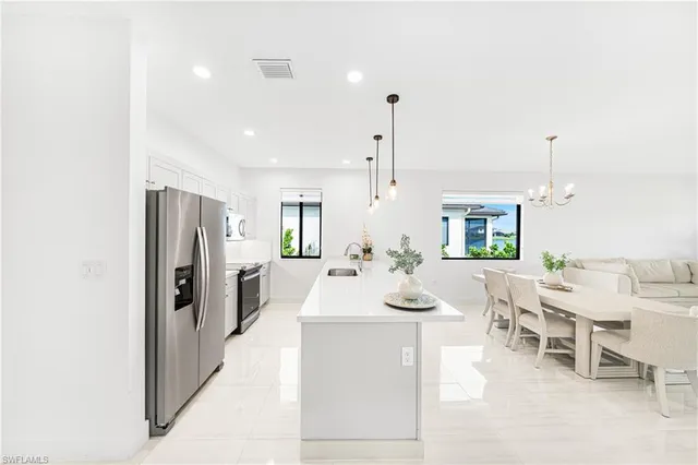 a view of a kitchen with kitchen island stainless steel appliances a table and chairs