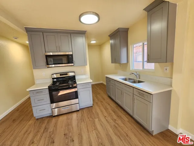 a kitchen with wooden floor and stainless steel appliances
