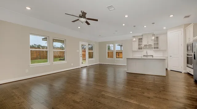 a view of an empty room with window and wooden floor