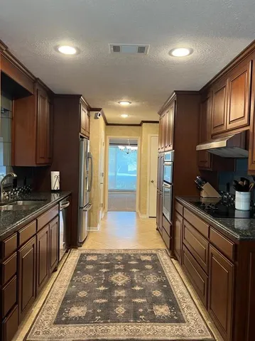 a large kitchen with stainless steel appliances granite countertop a refrigerator stove and sink