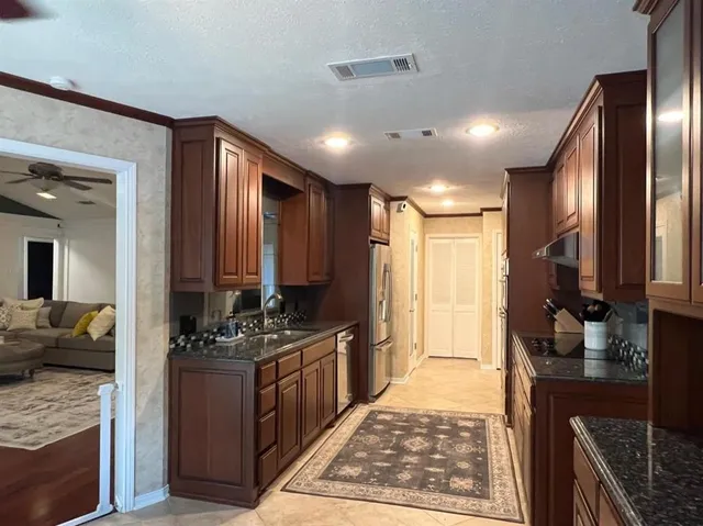 a kitchen with stainless steel appliances granite countertop a stove top oven a sink and a refrigerator