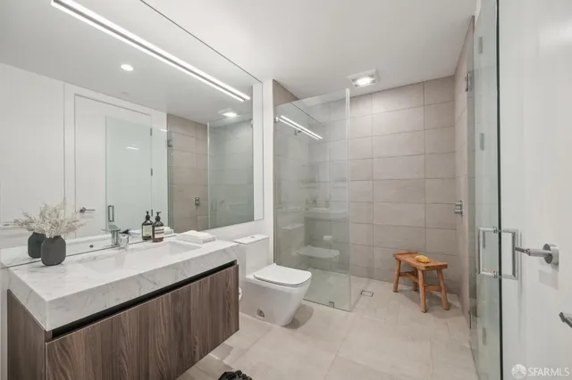 a bathroom with a sink a toilet a mirror and shower