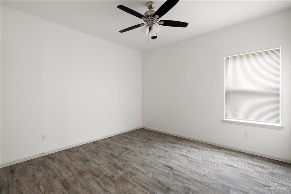 1020 Palm Drive, Unit 1 Alamo, TX 78516 - Photo 5 of 9 an empty room with wooden floor ceiling fan and windows