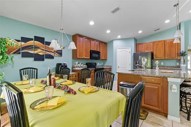 a kitchen with stainless steel appliances granite countertop a sink a stove a dining table and chairs
