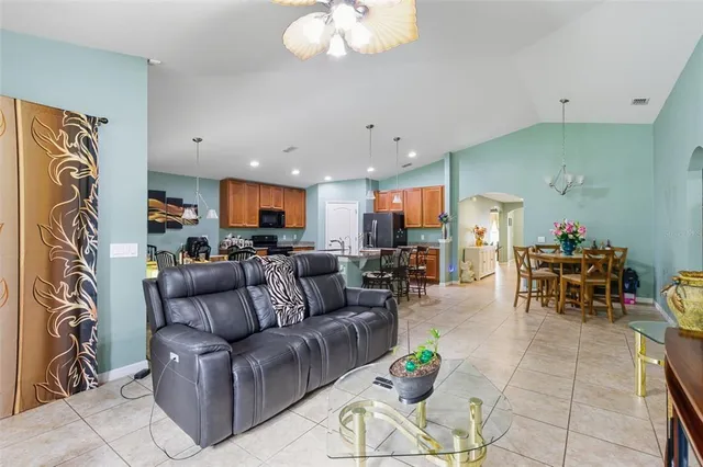 a living room with furniture kitchen view and a chandelier
