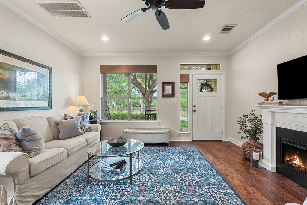 6708 Menchaca Road, Unit 2 Austin, TX 78745 - Photo 5 of 30 Living area featuring wood-finish flooring, a white mantel fireplace, a ceiling fan, and crown molding