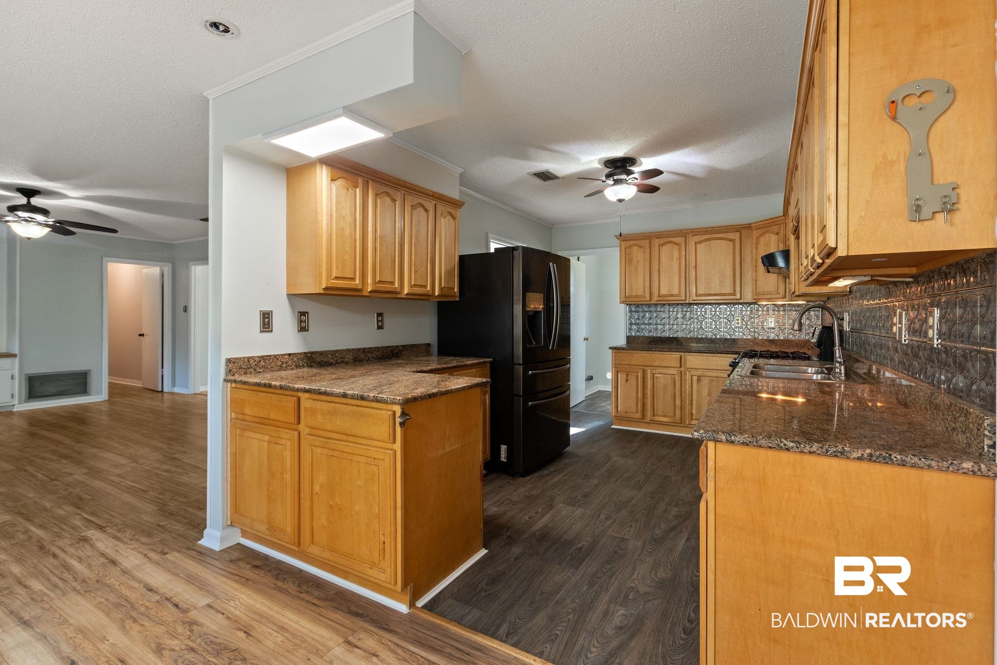 3864 Leroy Stevens Road Mobile, AL 36619 - Photo 9 of 33 Kitchen with ceiling fan, dark stone counters, black refrigerator with ice dispenser, dark wood-style floors, and ornamental molding