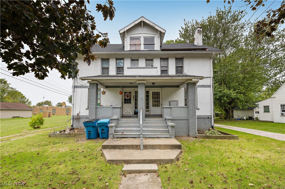 View of front of property with covered porch and a front yard