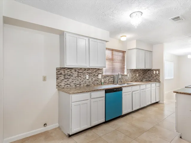 a kitchen with granite countertop a sink and white cabinets