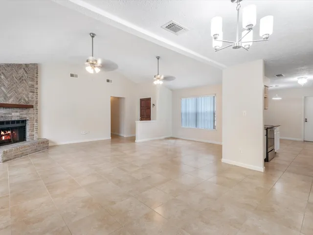 an empty room with chandelier fan and windows