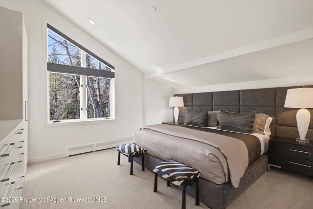 a bedroom with a bed two lamps and a large window