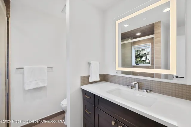 a bathroom with a granite countertop sink a toilet and a mirror