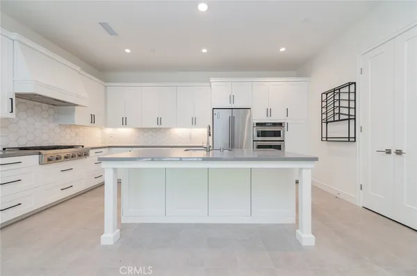 a kitchen with a sink a stove a refrigerator and white cabinets