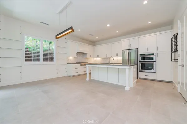 a large white kitchen with a refrigerator a stove a microwave and cabinets