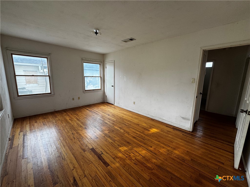 1010 South 17th Street Temple, TX 76504 - Photo 15 of 30 an empty room with wooden floor and windows