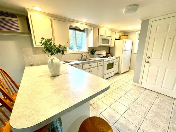 a kitchen with stainless steel appliances kitchen island granite countertop a table chairs and a refrigerator