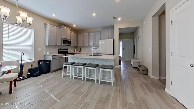 a kitchen with a table chairs wooden floors and a view of living room