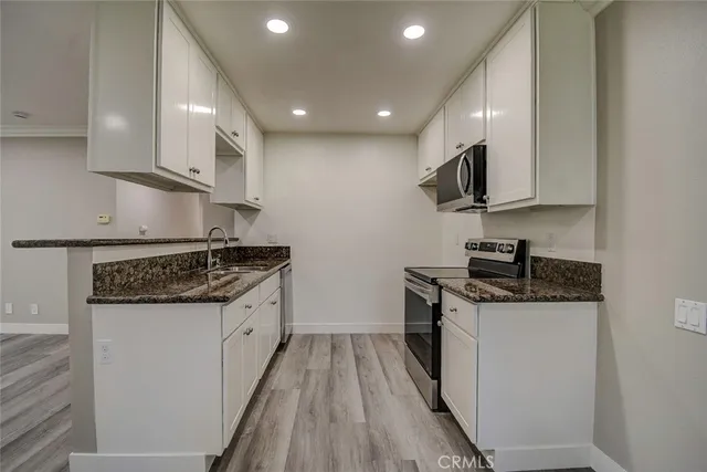 a kitchen with stainless steel appliances granite countertop a stove top oven a sink and a refrigerator