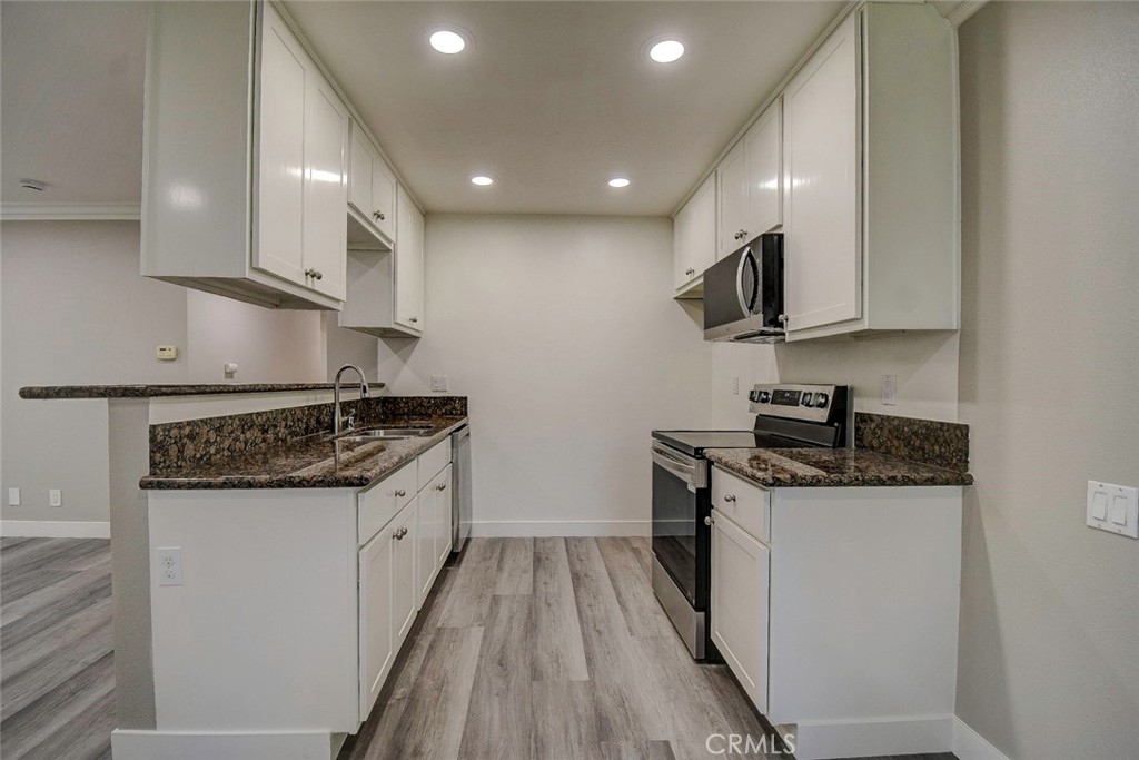 21941 Rimhurst Drive, Unit D Lake Forest, CA 92630 - Photo 7 of 44 a kitchen with stainless steel appliances granite countertop a stove top oven a sink and a refrigerator