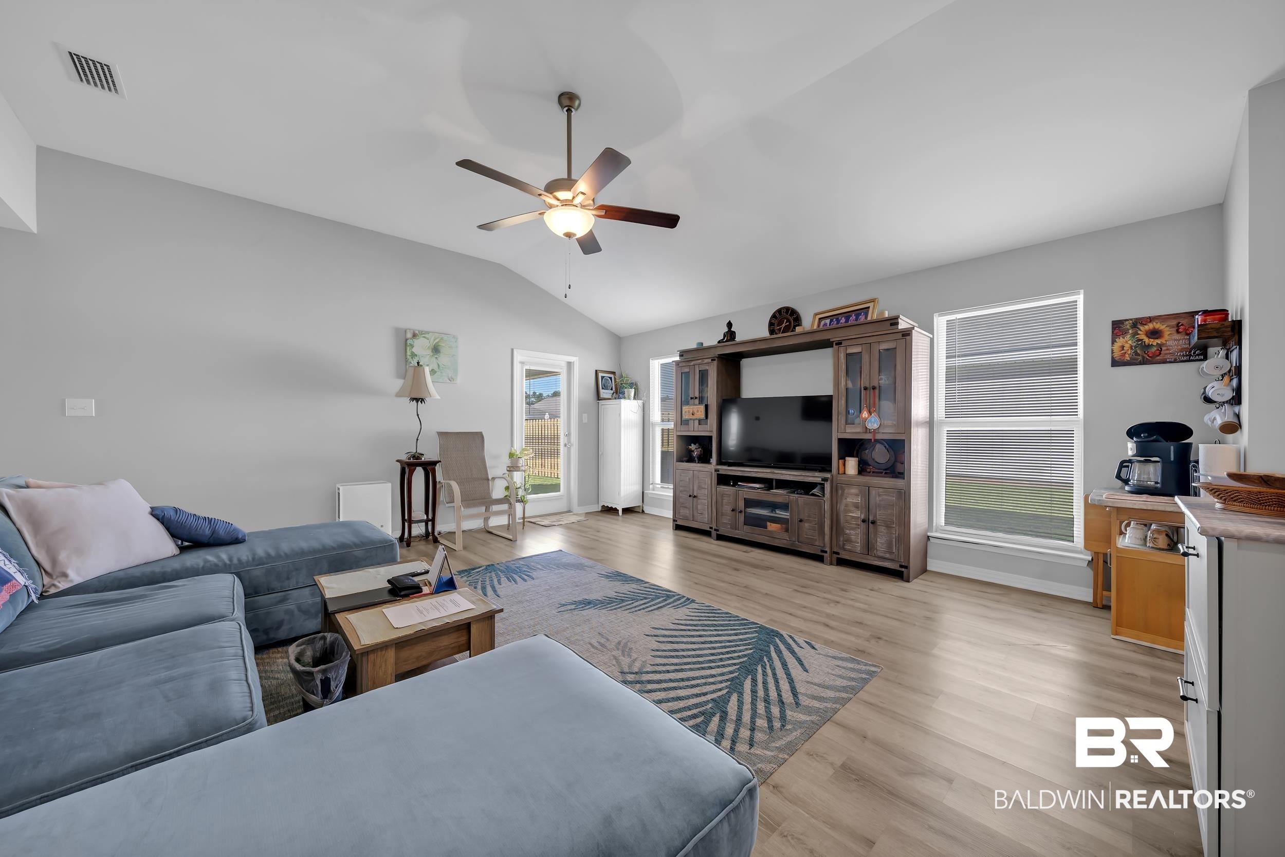 1228 Caper Avenue Foley, AL 36535 - Photo 15 of 54 Spacious living area featuring light wood-finish flooring, vaulted ceilings with a ceiling fan, and multiple windows with horizontal blinds
