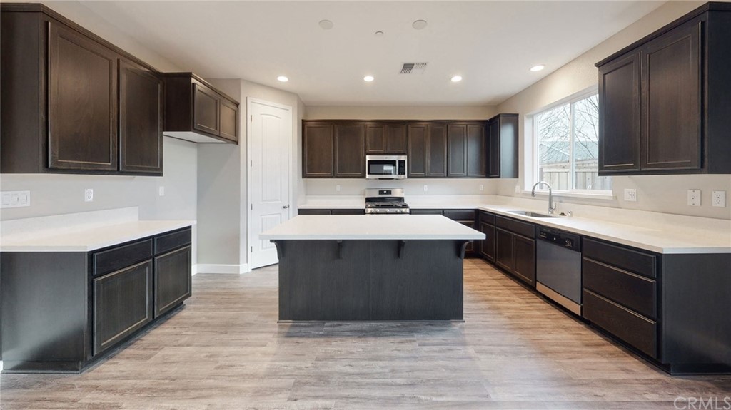 63 Bentwater Loop Chico, CA 95973 - Photo 15 of 20 a large kitchen with stainless steel appliances a sink dishwasher a refrigerator and a cabinets with wooden floor