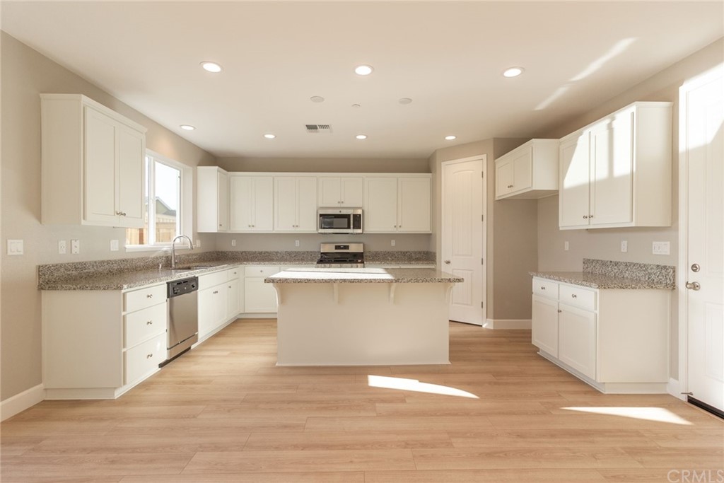 63 Bentwater Loop Chico, CA 95973 - Photo 4 of 20 a large kitchen with kitchen island a sink a center island stainless steel appliances and a counter top space