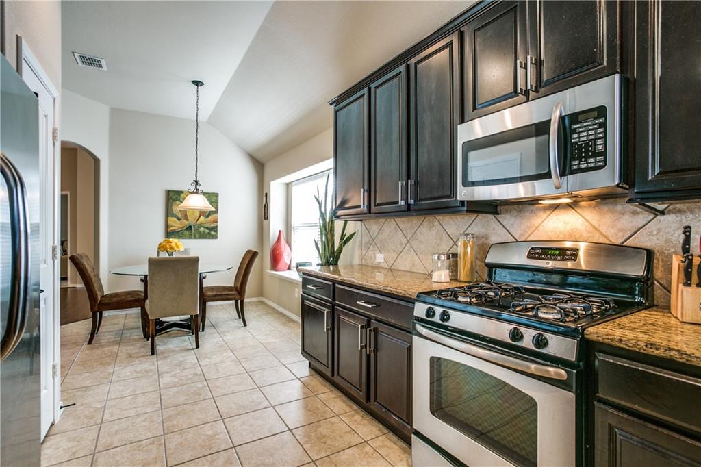 713 Setting Sun Trail McKinney, TX 75069 - Photo 9 of 25 a kitchen with granite countertop a stove top oven microwave and cabinets