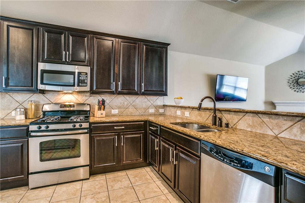 713 Setting Sun Trail McKinney, TX 75069 - Photo 10 of 25 a kitchen with granite countertop a stove top oven microwave and sink