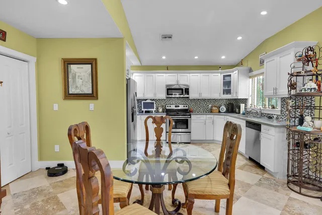 a kitchen with stainless steel appliances granite countertop a stove a refrigerator a kitchen island with a dining table and chairs