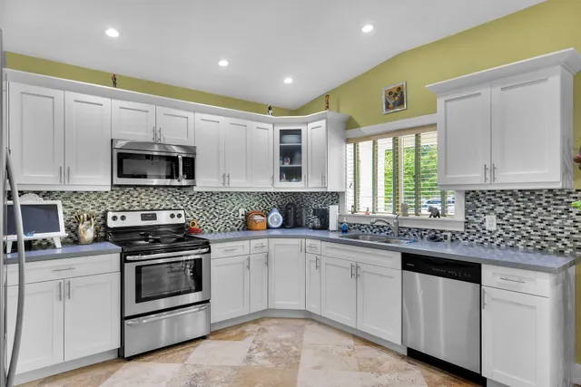 a kitchen with white cabinets appliances and a sink