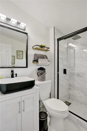 a bathroom with a toilet a sink a mirror and shower