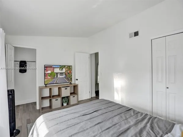 a bedroom with a bed and a flat tv screen on dresser