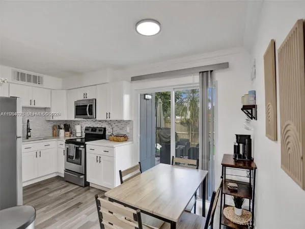a kitchen with stainless steel appliances a stove a sink a refrigerator white cabinets and wooden floor