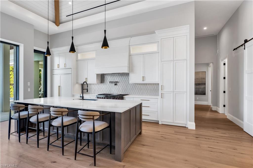 635 Harbour Drive Naples, FL 34103 - Photo 6 of 32 a kitchen with stainless steel appliances granite countertop a sink a stove a refrigerator and island with wooden floor