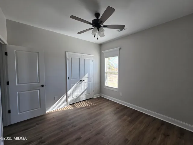 an empty room with wooden floor ceiling fan and windows