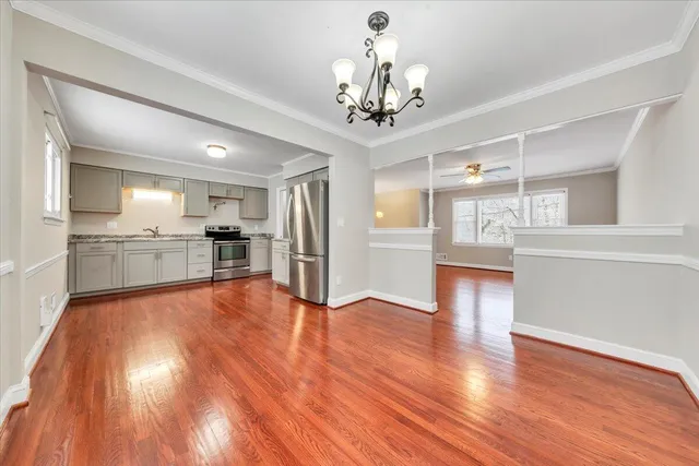 a view of an empty room with wooden floor and a ceiling fan