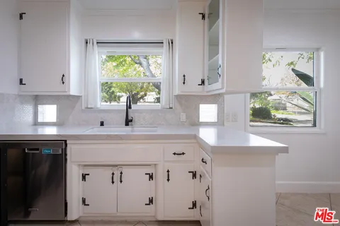 a kitchen with white cabinets a window and a sink
