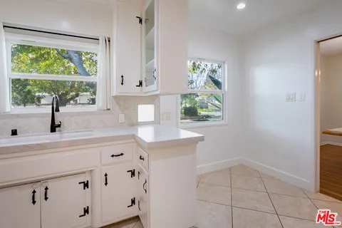 a kitchen with white cabinets and a window