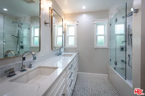 a bathroom with a tub sink shower and two mirror