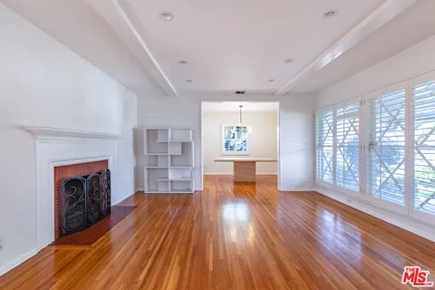 an empty room with wooden floor fireplace and windows