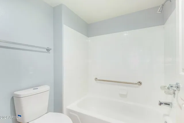 a white toilet sitting next to a bath tub