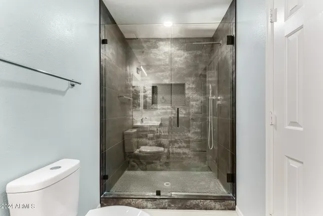 a bathroom with a granite countertop shower a toilet and a sink