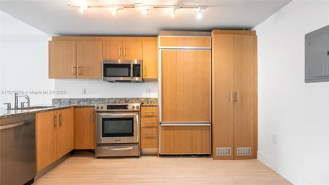 a kitchen with stainless steel appliances granite countertop a refrigerator a sink and a stove