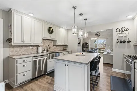 a kitchen with stainless steel appliances kitchen island granite countertop a sink a center island and cabinets