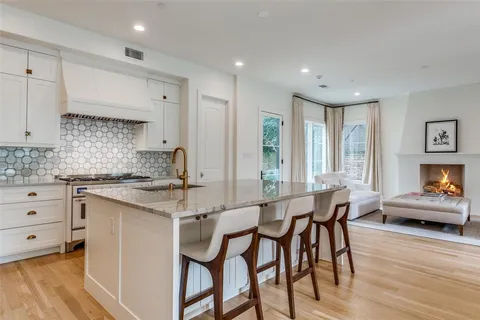 a kitchen with stainless steel appliances granite countertop a table chairs sink and cabinets