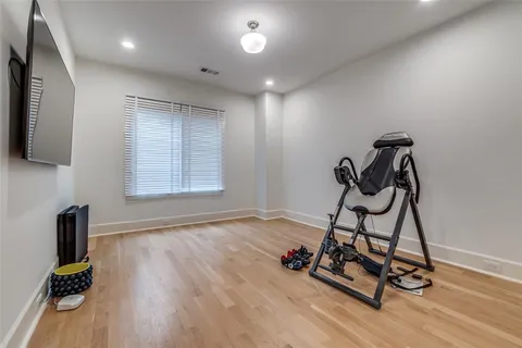 a view of a room with gym equipment and wooden floor