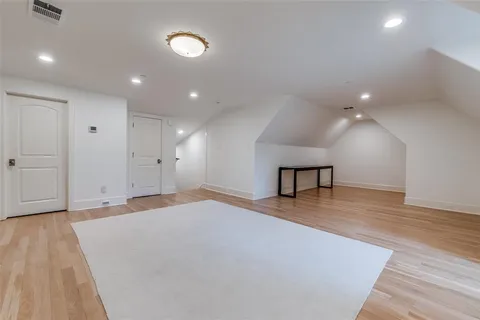 a view of an empty room with wooden floor and a ceiling fan